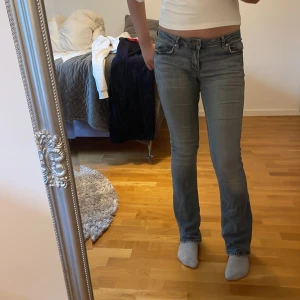 Blå bootcut jeans med låg midja - Snygga ljusblå jeans med bootcut-modell och låg midja. Jeansen har klassisk femficksdesign, dragkedja och knapp framtill. Materialet är denim och passformen är slim upptill med utsvängda ben. Perfekta för en avslappnad och trendig look. Det ända problemet är att sömmen vid midjan har gått upp lite men går att sy fast.