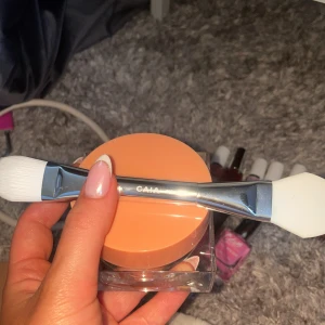 CAIA Red Carpet Face Mask + borste - Säljer en CAIA Red Carpet Face Mask från glow-serien, 50 ml, med vitamin E och jojobaolja. Kommer i en snygg genomskinlig burk med persikofärgat lock. Medföljer en CAIA applikatorborste med dubbla ändar, ena sidan i vit syntetborst och andra i silikon.