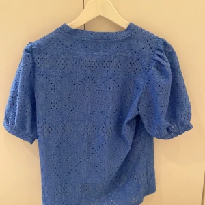 Blå spetsblus från Object😇 - Superfin blå blus från Object i storlek XS. Blusen har korta puffärmar och är helt täckt av ett broderat spetsmönster med fina detaljer. Rund halsringning och luftig känsla.                   Nypris: 300kr och mitt pris 150kr🥰