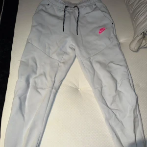 Nike tech fleece mjukisbyxor  - Snygga ljusblå/vita mjukisbyxor från Nike med svart snörning i midjan och en rosa Nike-logga på låret. Byxorna har elastisk midja, praktiska fickor och är tillverkade i mjukt material som är perfekt för chill eller träning. Knappt använt därav nyskick. Köpta från jd sports. 