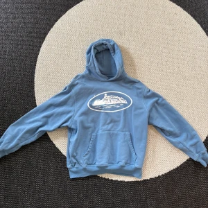 Cortiez hoodie ljusblå - Skit fett Cortiez hoodie, perfekt för sommarkvällarna och sitter riktigt snyggt. Säljer den pga att jag bytat stil. Pris är ej spikat och ställ gärna frågor. Passar både S och M