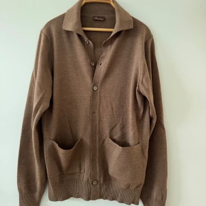 Stenströms merinoull cardigan  - Klassisk brun kofta från Stenströms i mjuk ull. Modellen har knappar framtill, två stora fickor och en snygg krage. Perfekt för lager-på-lager och passar till det mesta. Långärmad och med ribbade muddar för extra stilpoäng. 1100 nypris isch 