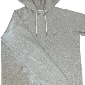 Grå hoodie från Quiksilver - Snygg ljusgrå hoodie från Quiksilver med klassisk känguruficka och vit snörning i huvan. Tröjan har diskret broderad logga på bröstet och är tillverkad i mjuk bomullsmix. Perfekt för chill dagar eller när du vill ha en clean streetstyle.