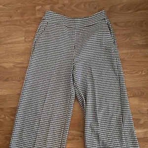 Rutig vida byxor från Zara Basic - Snygga svartvita vida byxor från Zara Basic med klassiskt hundtandsmönster. Byxorna har hög midja och raka, breda ben för en trendig look. Perfekta att styla med en enkel topp eller stickad tröja.