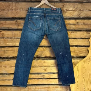  Dondup  - Snygga blå jeans från Dondup. Jeansen har orange kontrastsömmar, unika detaljer på bakfickorna och diskreta slitningar samt färgstark som gör dom lite extra stiliga. Perfekta för dig som gillar lite stiligare jeans 