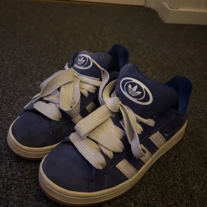 Blå adidas campus - As fina blåa adidascampus i storlek 38 2/3, använt fåtal gånger och ser ut som nya. Tjocka vita skosnören. Kom tyvärr inte till användning mer
