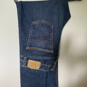 Nudie Jeans - Säljer ett par klassiska mörkblå jeans från Nudie Jeans. Modellen har normal regular passform som sitter bra utefter benen. Storleken är 30/34 och passar om man är lite längre. skicket är utmärkt då de endast är använda 2-3 gånger. Bara att skriva om någon fråga skulle uppstå 🌟