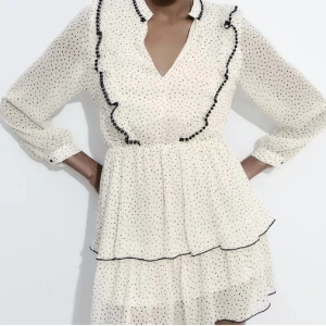 klänning från Zara - Supersöt vit kortklänning från Zara med svarta prickar, volangdetaljer och v-ringning. Den blir aningen kort för mig som är 174 cm lång. Skulle säga att den är mer som en strl M 🩷