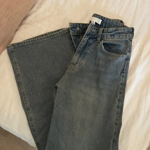 Wide jeans från H&M i blå denim - Säljer ett par blåa wide jeans från H&M i storlek 34. Jeansen har hög midja, klassisk femficksdesign och är tillverkade i denim. Perfekta för dig som gillar en avslappnad och trendig look.