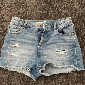 Blå jeansshorts med slitningar - Snygga blå jeansshorts från Lindex. Är i storleken 146/152 men passar mig som normalt sätt har storlek xs. 