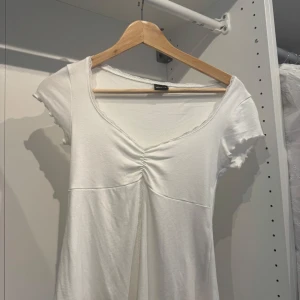 Vit croppad topp med spetsdetaljer - Supersöt vit croppad topp från Gina Tricot med korta ärmar, v-ringning och spetskant. Använd en gång, väldigt bra skick💞