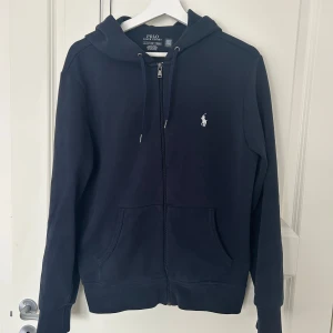 Blå Ralph lauren zip hoodie - Hej! Säljer denna riktigt snygga blåa zip hoodien från Ralph Lauren. Den är i storlek S. Tröjan har inga defekter på sig eller något liknande. Hör bara av dig om du har någon fråga!