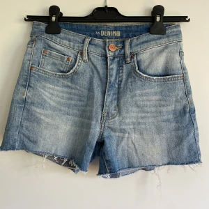 Blå jeansshorts från Denim 1953 - Snygga blå jeansshorts från Denim 1953. Shortsen har normal passform och är tillverkade i slitstarkt denimtyg. Storlek 34