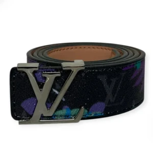 Louis Vuitton svart skärp med LV-spänne - Snyggt svart bälte från Louis Vuitton med ikoniskt LV-spänne i metall. Bältet har ett diskret mönster med inslag av lila och grönt samt klassisk monogramdesign. Tillverkat i exklusivt skinn med en lyxig känsla och cool look.