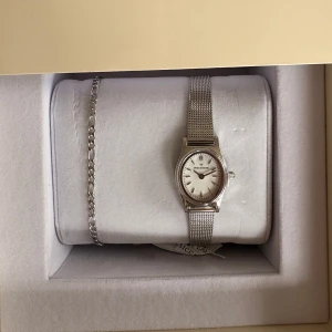 Mockbergklocka - Stilren och minimalistisk klocka från Mockberg i silver med mesharmband och rund urtavla. Medföljande armband. Allt i rostfritt stål. Kommer ej till användning. HELT NY MED PRISLAPP!!!