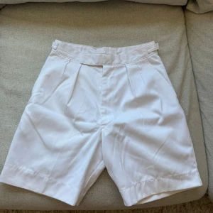 Vita Royal Navy shorts från Broadway & sons  - Snygga vita RN shorts med hög midja och pressveck från Broadway & sons. Rak passform, bälteshällor och bakficka med knapp.