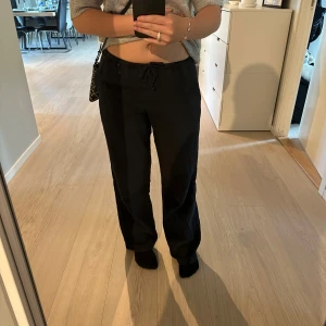 Svarta linnebyxor med snörning - Säljer ett par svarta linnebyxor med avslappnad passform och dragsko i midjan. Byxorna har raka ben och är perfekta för en chill och stilren look. Materialet är lätt och andas, vilket gör dem sköna att bära hela dagen. Dem är från ginas barnavdelning men sitter som en xs. Jag är 160 cm lång.