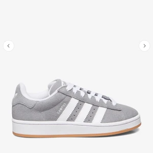 Adidas Campus 00s -  Om du ber om bilder skickar jag!! Använda men ändå fina. Säljs för att ingen användning , kan diskutera pris! Snygga adidas Campus sneakers i grå mocka med klassiska vita ränder och vit sula. Skorna har rund tå, snörning och en stilren design som passar till det mesta. Perfekta för dig som gillar en clean och tidlös look.