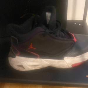 Svarta Nike Air Jordan sneakers - Säljer ett par svarta Nike Air Jordan sneakers med röda detaljer och vit sula. Skorna har klassisk Jordan-logga på sidan och 'Flight' broderat på plösen. Snygg sportig look med snörning och bekväm passform, perfekta för dig som gillar streetwear.