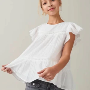 Vit blus med volangärmar Gina Tricot - Supersöt vit blus från Gina Tricot i luftig bomull. Blusen har volangiga korta ärmar, rund halsringning och fina spetsdetaljer. Den är lätt utställd och har en flowy känsla, perfekt för en fräsch och somrig look. Är i storlek 146/152 passar även storlek 158 eftersom att den är pösig.