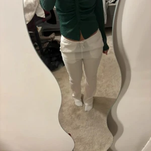 Grön kofta från Stradivarius M - Säljer en grön kofta från Stradivarius i storlek M. Koftan har lång ärm, smockad struktur och knappar framtill. Modellen är croppad och har en snygg rynkad detalj längs mitten. Perfekt att styla med jeans eller kjol.