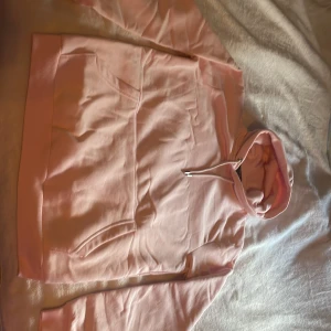 Ljusrosa hoodie från new yorker/SMOG, storlek M - Säljer en ljusrosa hoodie från SMOG/new yorker i storlek M. Tröjan har huva med snörning, magficka och ribbade muddar vid ärmslut och nederkant. Perfekt för dig som gillar en clean och enkel stil. Materialet är mjukt och skönt, troligtvis bomullsmix. Helt ny har bara provat den, finns en liten orange prick på baksidan, men det går nog bort i tvätten (inte säker men kanske)  jag köpte den för 199, men säljer för 149 pga pricken ❤️