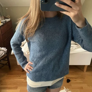 Blå stickad tröja med mönster - Mysig blå stickad tröja med diskret vågigt mönster. Tröjan har rund halsringning och långa ärmar, perfekt för lager-på-lager och chill dagar. Passformen är normal och materialet känns mjukt mot huden.