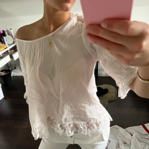 Babyrosa blus med spetsdetaljer - Säljer en luftig rosa blus med vackra spetsdetaljer vid ärmslut och nederkant. Blusen har trekvartsärmar och en lös passform, perfekt för vår och sommar. Baksidan har ett fint spetsmönster💗