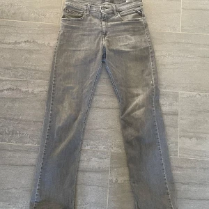 Grå jeans från Replay - Säljer ett par grå jeans från Replay med modellen Thad med klassisk femficksdesign och raka ben. Jeansen har normal passform och är tillverkade i denim med snygg tvättad look. Perfekta för en avslappnad stil. Skriva för fler bilder.