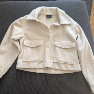 Beige fleecejacka från Vero moda - Mysig beige fleecejacka från  Vero moda med två stora fickor framtill och krage. 