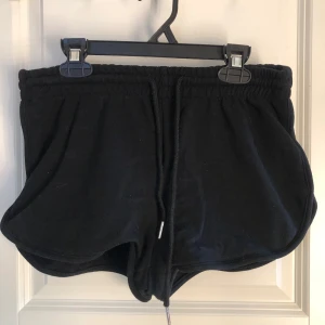 Svarta shorts  - Svarta shorts från SHEIN med elastisk midja och dragsko i storlek s . Modellen är kort och har en rundad form vid benen. Perfekta för varma dagar eller som mysplagg hemma 🖤