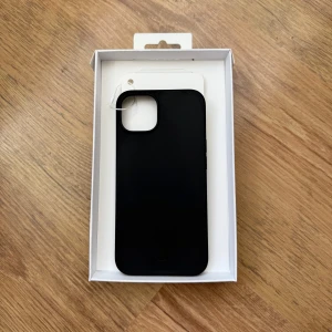 Helt ny: Svart mobilskal från dbramante1928 - Säljer ett svart, slimmat mobilskal till iPhone 13 från dbramante1928. Skalet är gjort av 100% återvunnen plast och har en stilren design som skyddar mobilen utan att göra den klumpig. Perfekt för dig som vill ha ett miljövänligt val! Skalet är helt nytt, aldrig använt. 