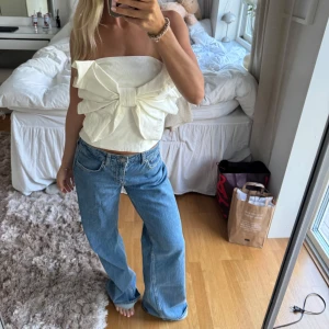 Vit axelbandslös topp med stor rosett - Säljer denna så fina topp med rosett perfekt i sommar!!. Endast använd 1 gång💕💕💕