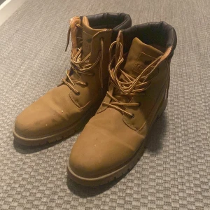 Bruna boots Timberland - Säljer ett par klassiska bruna boots från Timberland med snörning och kraftig sula. Skorna har rund tå och är perfekta för höst och vinter. Mjukt vadderat skaft och slitstark design. Lite smutsiga men rengörs innan dom blir sålda 