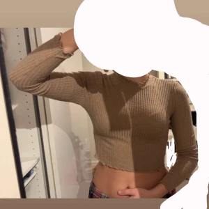 Beige långärmad topp SHEIN - Säljer en beige ribbad croppad topp med långa ärmar och volangkant vid hals, ärmslut och nederkant. Perfekt för lager-på-lager och enkel att matcha med olika outfits. Är för liten på mig. Passar S och XS 