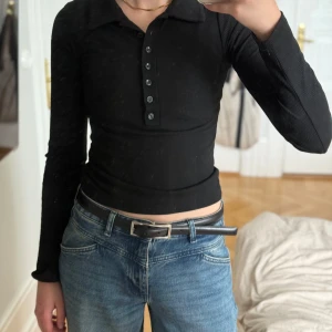 Svart långärmad tröja - Säljer denna svarta långärmade tröja med knappar och krage, den är endast använd ett fåtal gånger och är i mycket fint skick!