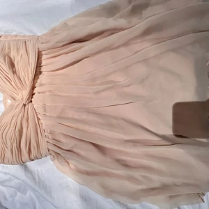  axelbandslös klänning  från NLY Trend - Säljer en romantisk axelbandslös klänning i champagnefärg från NLY Trend. Klänningen har vackert draperad överdel och ett lätt, svepande tyg i kjolen. Perfekt för speciella tillfällen och ger en elegant känsla.sitter väldigt fint på o fin till sommaren. Köpte men passa tyvärr inte 😊