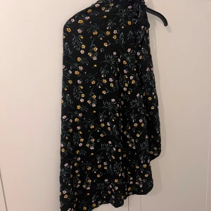 Svart blommig kjol - Svart kjol med blommor på, knytband på sidan.