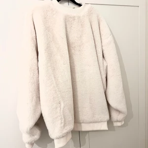 Vit fluffig tröja från ASOS - Supermjuk och oversized vit tröja från ASOS i fluffigt material. Perfekt för kalla dagar med sin mysiga känsla och breda passform. Ribbad mudd vid hals, ärmslut och nederkant. Enkel och stilren design. Nypris: 799kr