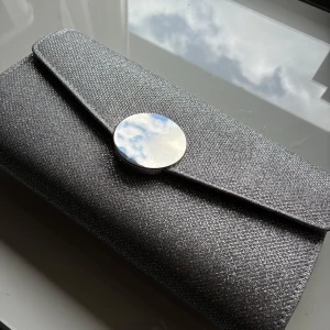 Bal väska✨ - 25 x 14 cm🩶Kuvertväska från Tiamo med glittrig yta. Väskan har en kedja som axelrem och ett innerfack för småsaker. Använd en gång innan på en bal, metallspännet är lite repigt men syns bara vid noga granskning. Nypris 500kr