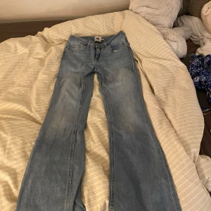 Blå bootcut jeans från lager 157 - Säljer ett par klassiska blå lager 157 jeans med bootcut passform. Jeansen har fem fickor, dragkedja och knapp framtill samt slitningar för en cool look. Perfekta för dig som gillar en tidlös stil.