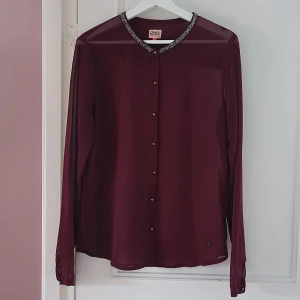 Vinröd transparent blus med pärlkrage från ONLY - Vinröd blus från ONLY med transparent material och extra glittriga detaljer.