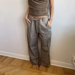 Beiga linnebyxor med snörning - Säljer ett par beiga linnebyxor med avslappnad passform och snörning i midjan. Byxorna har raka ben och fickor fram samt bak. Perfekta för varmare dagar och ger en chill vibe.