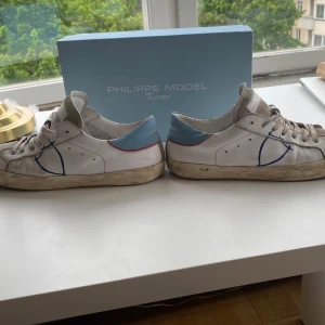  Philippe modell  - Säljer ett par vita sneakers från Philippe Model Junior storlek 39 men kan passa 40 .som ni ser har den defekter på varsin sko. De är lite smutsiga men det mesta går bort med våtservetter. Box ingår 💯pris kan diskuteras 