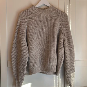 Beige stickad tröja från H&M - Säljer en beige stickad tröja från H&M i storlek M. Tröjan har en högre halsringning och är långärmad med en rak, något loose passform. Perfekt för lager-på-lager och enkel att matcha med olika outfits. Lite nopprig på vissa partier, se bild men ändrar inte helhetsintrycket. 😊