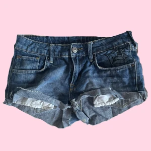 Lowrise jeansshorts med handritade detaljer på fickorna - Säljer ett par lågmidjade blå jeansshorts med råa kanter och handritade detaljer på fickorna. Detta är mina favvo shorts men jag passar inte dom längre. Storleken på dessa är väldigt små, dom passade mig när jag var 14 år och vägde under medelsnittet så keep that in mind! Dom är väldigt diy så de är också något att tänka på! 🌸