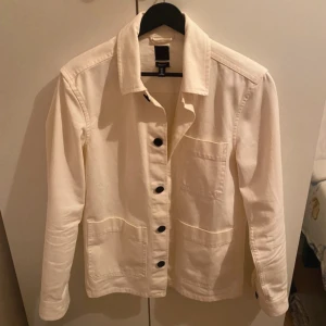 Vit overshirt  - Stilren vit overshirt från H&M med regular fit. Jackan har långa ärmar, knäppning framtill med svarta knappar och klassisk krage. Perfekt att slänga över en t-shirt för en clean look. Storlek XS och skick 10/10. Pris kan diskuteras vid snabb affär! 