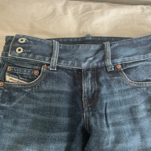 Blå bootcut jeans från Diesel - Säljer ett par klassiska blå bootcut jeans från Diesel med låg midja och dubbla knappar i linningen. Jeansen har fem fickor❤️
