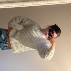 Vit stickad tröja med fransar - Säljer en grå stickad tröja med fransdetaljer på axlarna. Tröjan har en rak, lite boxig passform och långa ärmar. Perfekt för dig som gillar en mysig och trendig look. Passar till jeans eller kjol! Köpte den 2 år sedan och använde den ungefär 10 gånger.