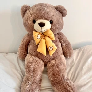 Stor nallebjörn med rosett - En stor och kramgo nallebjörn med en gul rosett runt halsen. Perfekt som present eller som en mysig kompis.  120cm lång.